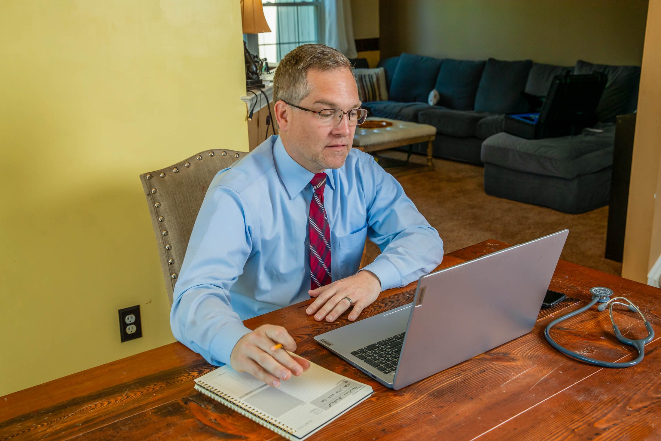 A man checking the laptop and taking notes